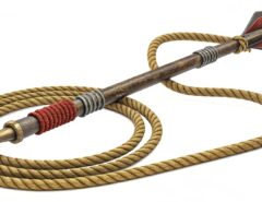 A traditional rope dart weapon with a long cord attached to a pointed metal dart, coiled neatly for display.