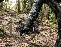 A grey hardtail mountain bike resting on a dirt path against mountains.