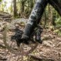 A grey hardtail mountain bike resting on a dirt path against mountains.