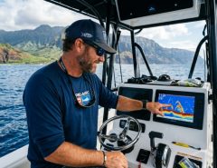 Angler viewing a fish finder screen on a boat in Hawaii.