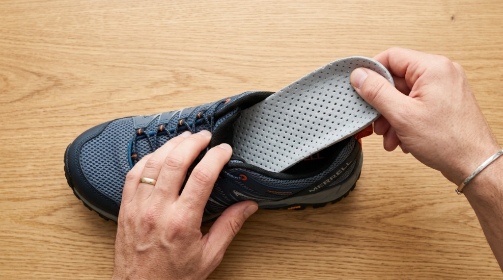 Person removing removable cushioned insole from a blue water shoe.