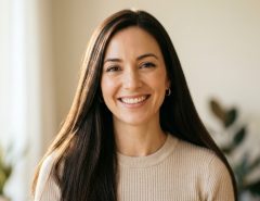 Woman smiling with sleek, smooth, and frizz-free hair in daylight.