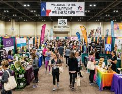 Visitors walking through a busy wellness expo with colorful vendor booths in Grapevine, Texas
